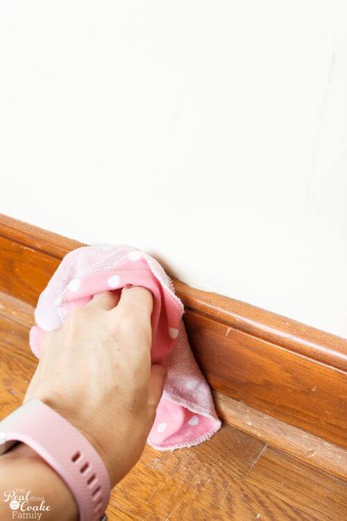 Picture showing cleaning trim with cloth Such a great guide on how to paint trim! It goes step by step on how to complete this simple DIY and make pretty changes in my home decor.