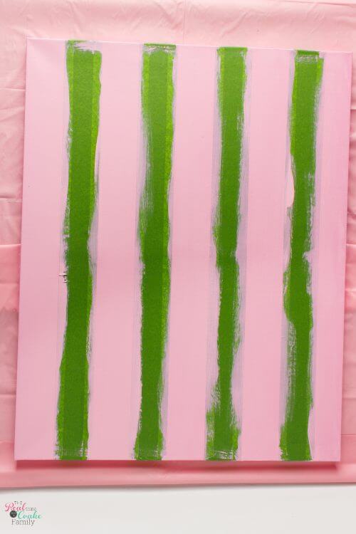 canvas painted with first stripes and tape still on Step by step tutorial on how to paint gingham and make the cutest wall art out of a craft store canvas. Perfect craft project to make DIY wall art.